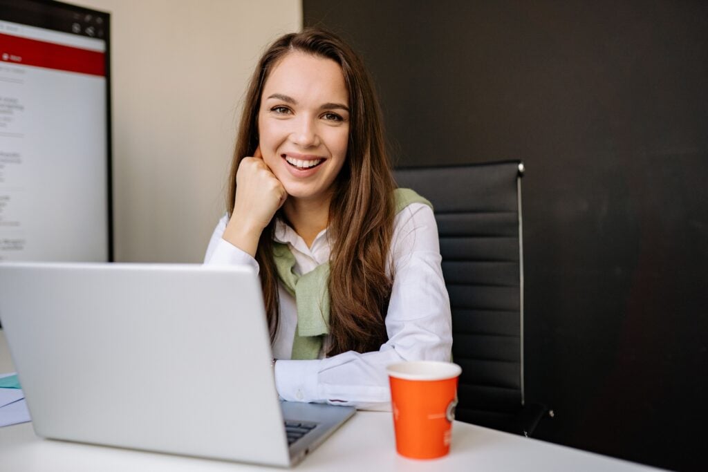 Lady sitted at a computer desk smiling at the camera